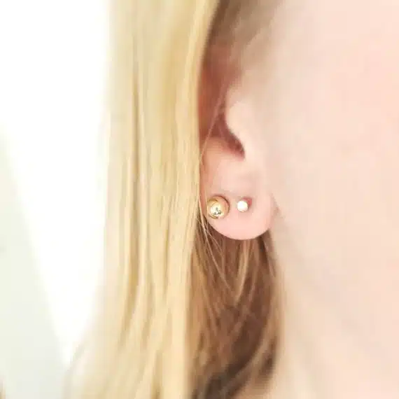 a girl wearing gold studs in the ear