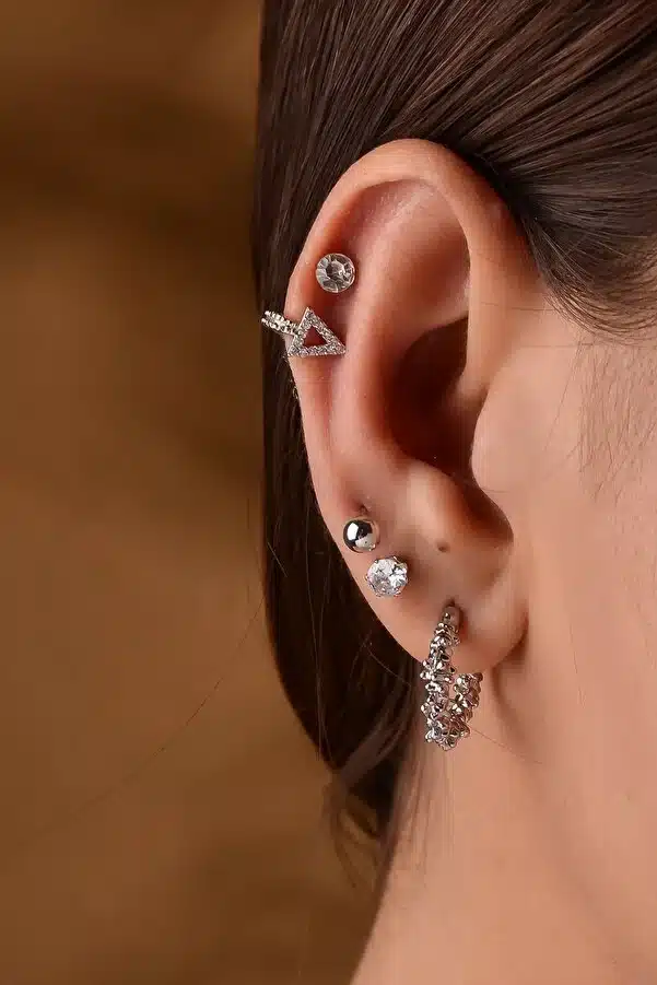 a women wearing barbell earrings in her ear with different peircings