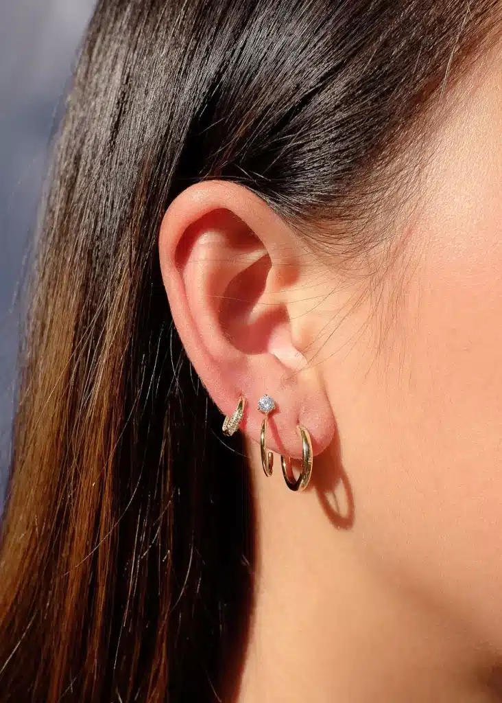 a women wearing gold three different hoop earrings 