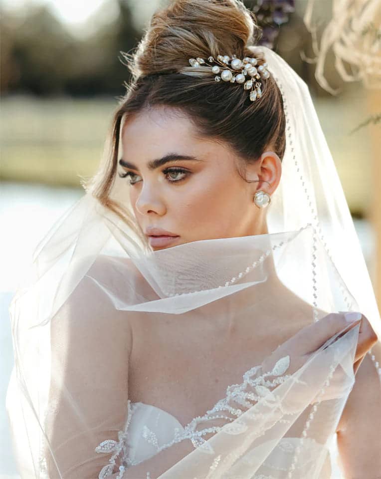 a bride posing for a picture wearing classic pearl studs with a net gown