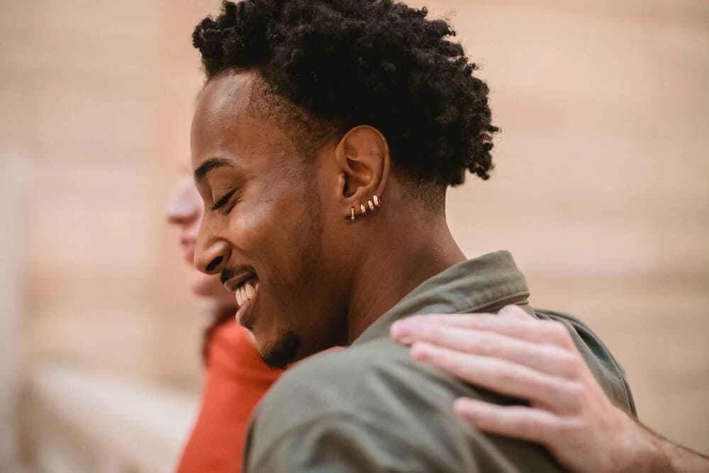 a guy with a smiling face wearing earring multiple earrings in his left ear