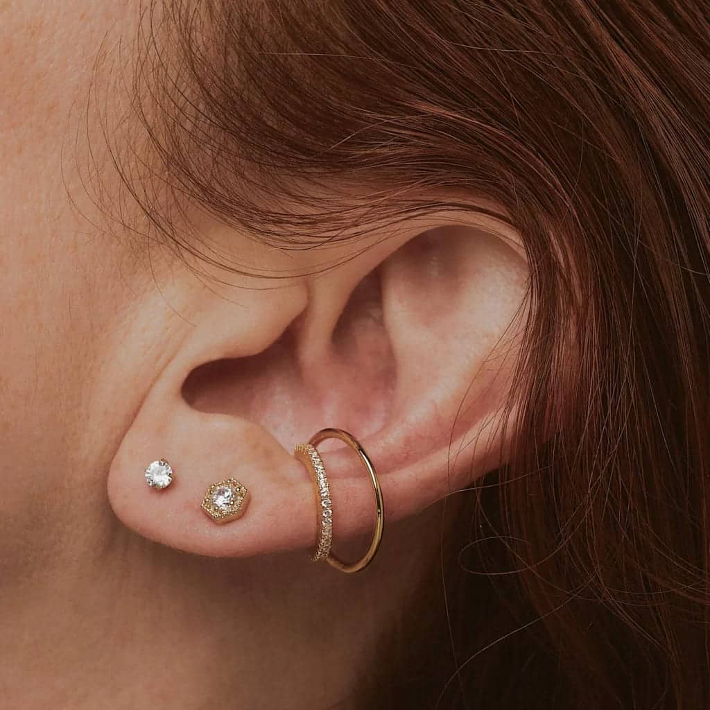  an ear of a lady wearing different types of earrings