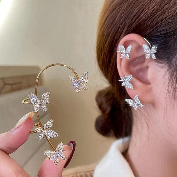 a lady showing butterfly Ear Cuffs one in her ear and one in her hand 