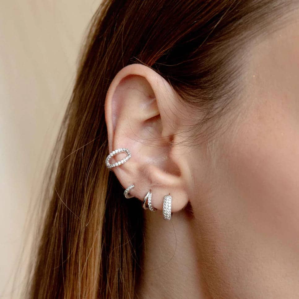 a lady wearing four different types of silver cartilage hoop earrings