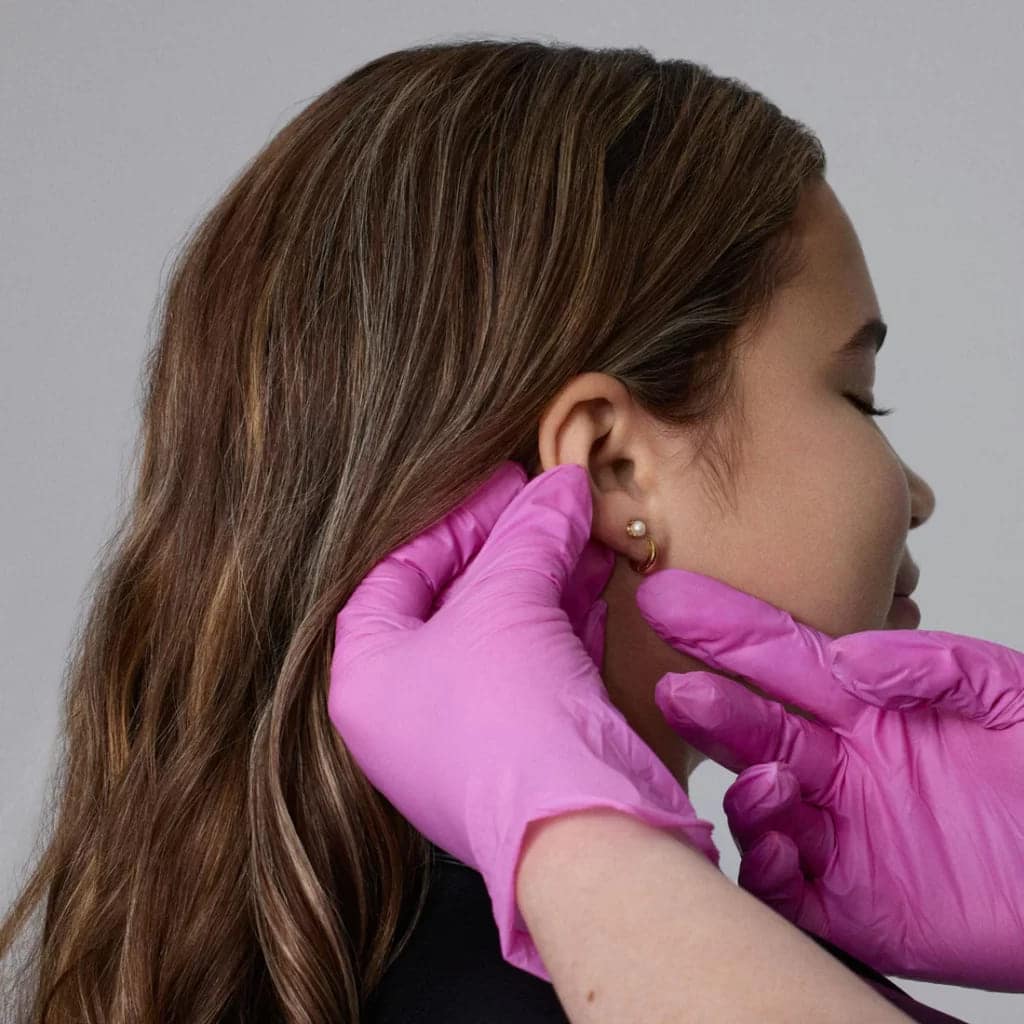 a professional examining the ear piercing