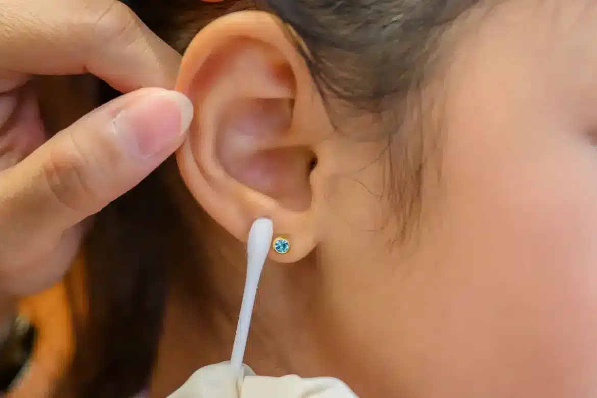 A_lady-cleaning-ear-piercing-with-a-cotton-swab A lady cleaning ear piercing with a cotton swab