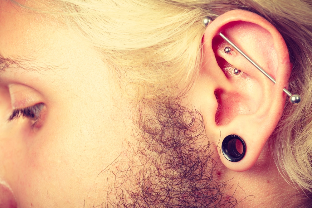 Pierced man ear with black plug tunnel industrial and rook