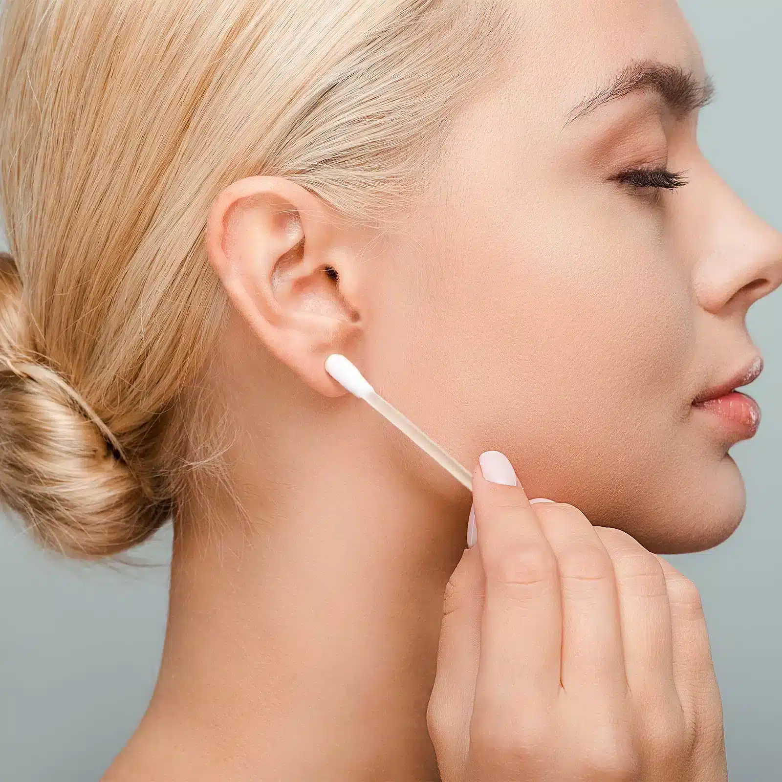 a lady cleaning her earring hole with a cotton swab