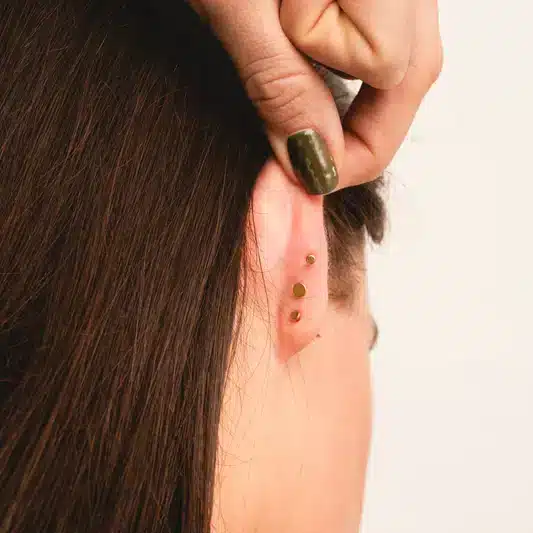 a lady showing the back of ears having flat back earrings