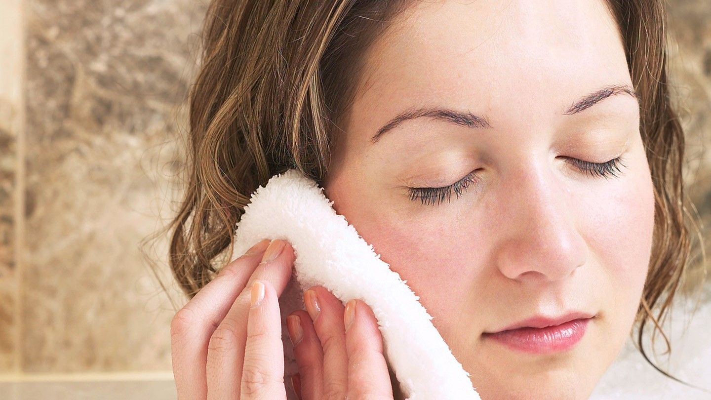 a lasy cleaning her ear with a white towel