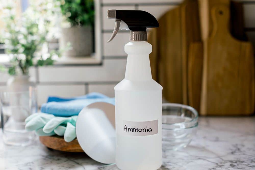 a spray bottle with ammonia solution with a bowl and gloves