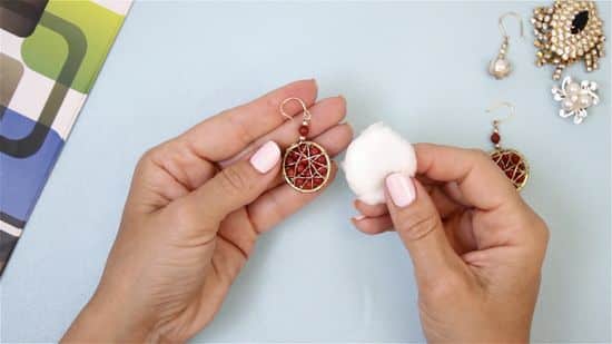 a lady holding cotton in one hand and earring in other 