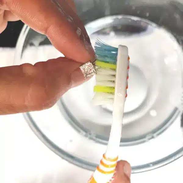 scrubbing diamod earrings using a tooth brush