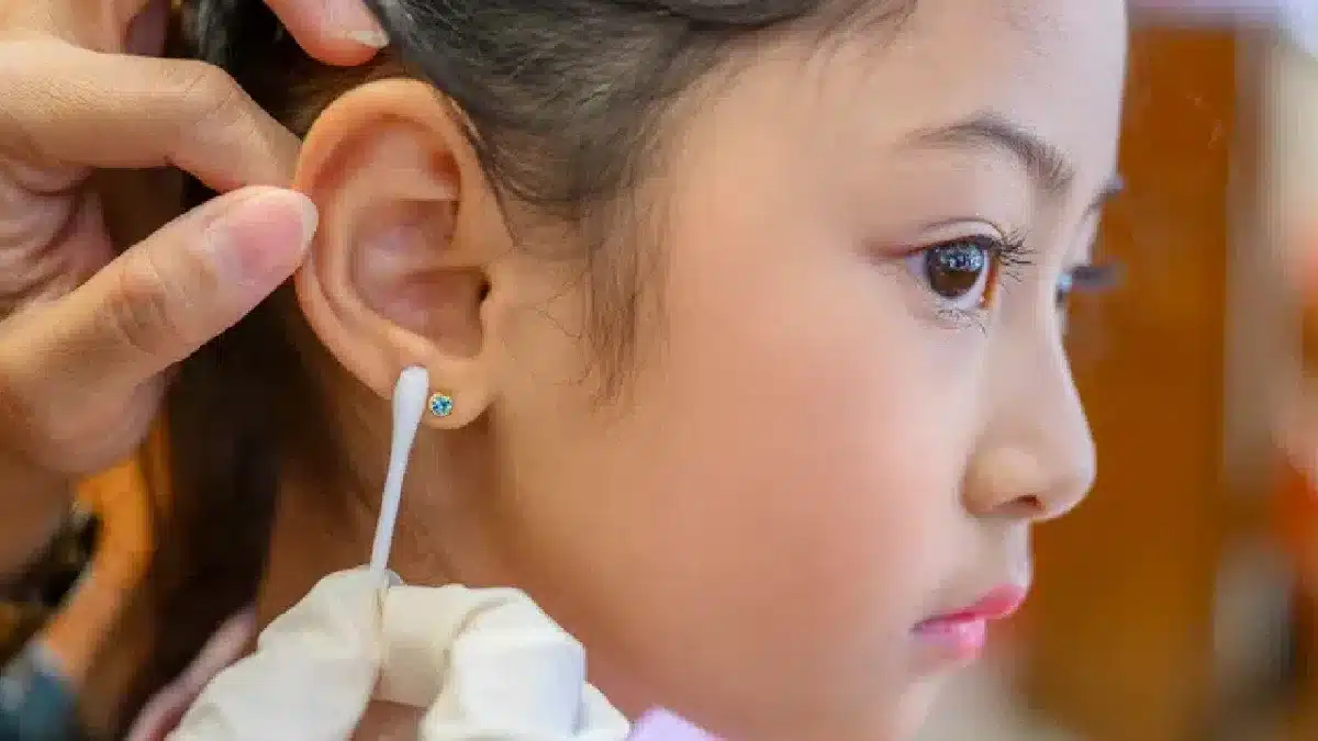 close up a hand with cotton pad cleaning the ear of a baby girl