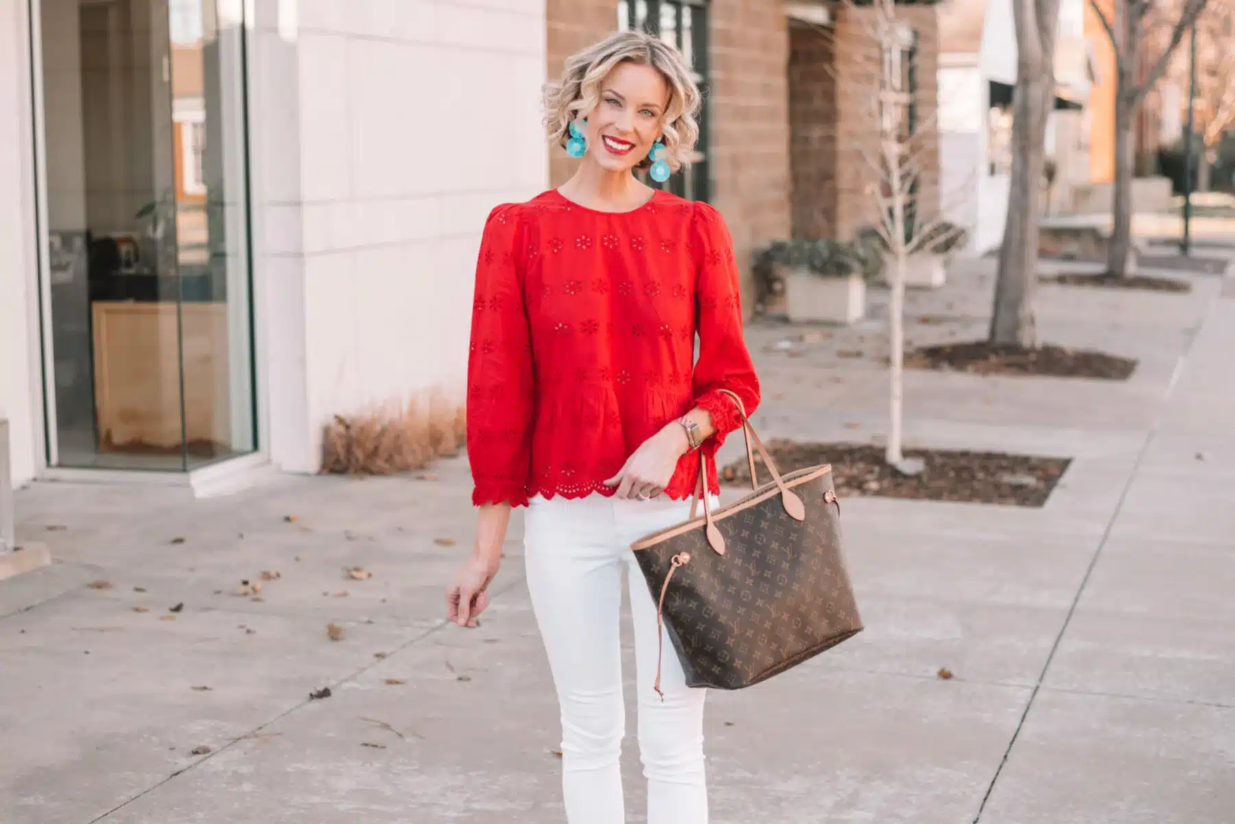 a girl wearing top with funky earrings white pants and carrying a bag